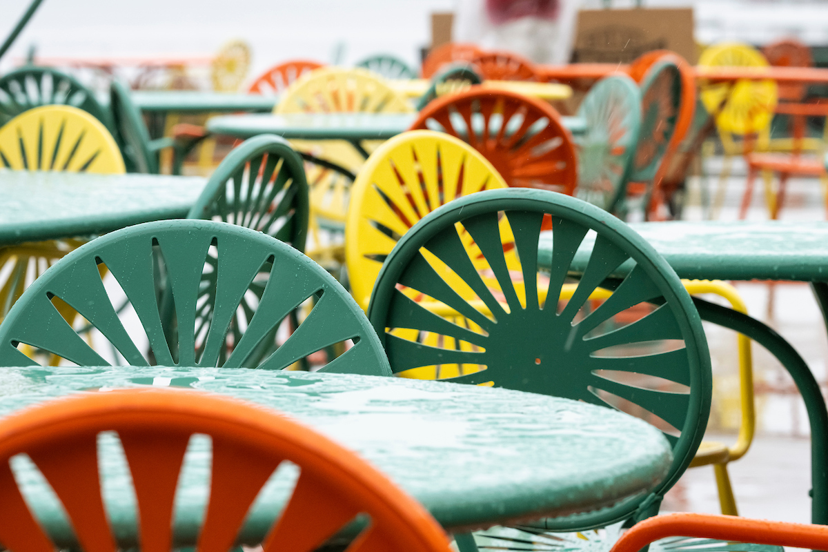 Rain puddles form on tabletops as movers and volunteers begin to unload truckloads of iconic Terrace chairs, previously stored for the past winter, and distribute them at the Memorial Union Terrace.
