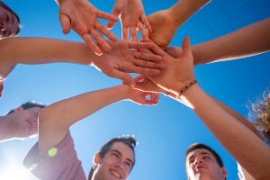 Students bring their hands together in a pre-game huddle.