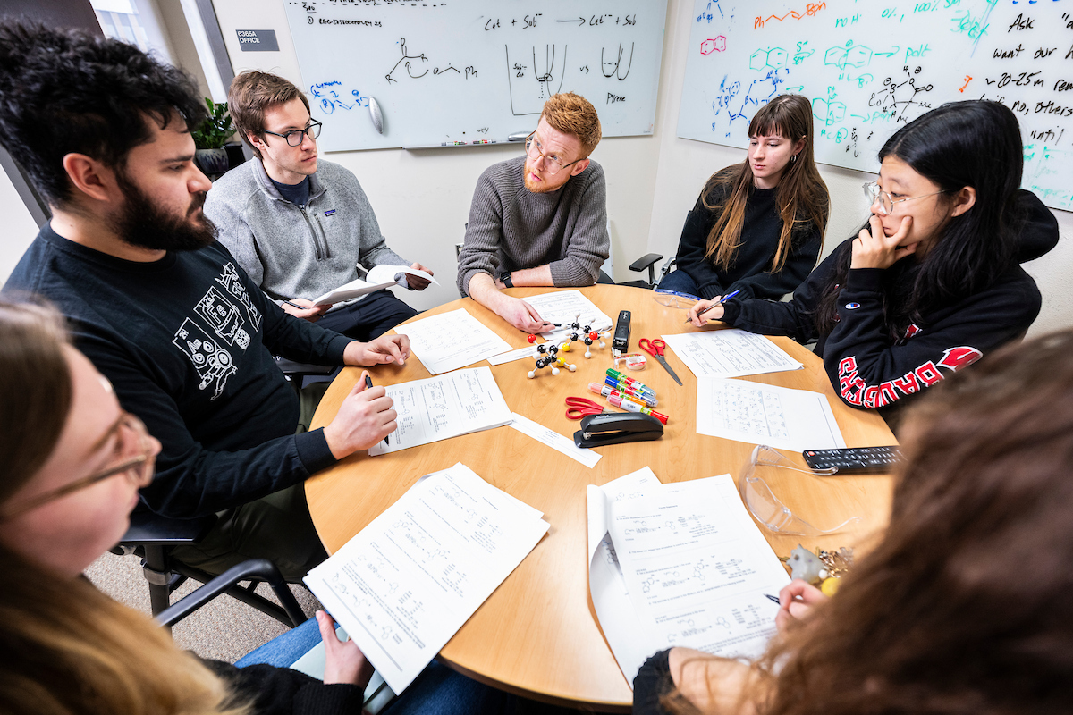Zachary Wickens (at center wearing eyeglasses), associate professor of chemistry in the College of Letters & Science, holds a team meeting with undergraduate and graduate students working in his lab